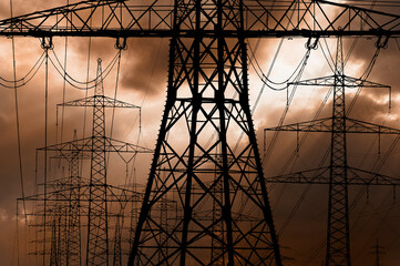 high voltage electric poles against sky with dramatic clouds