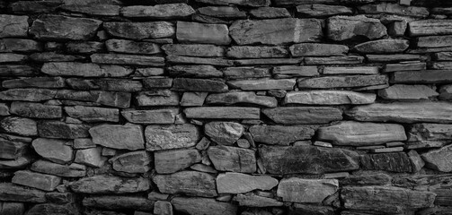 Empty monochrome black and white (dark gray) grain stone wall for abstract  background and texture. beautiful patterns, space for work, banner, wallpaper close up.