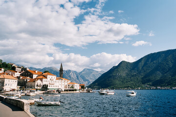 Many excursion boats with canopies are moored off the coast of Perast with views of the mountains....