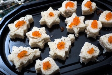 Closeup of appetizers toast with salmon and lumpfish roe in a black plate	