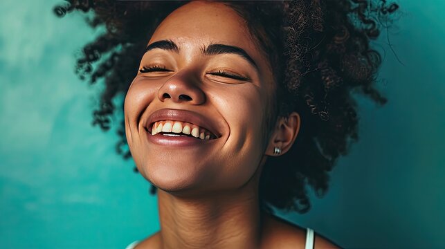 A genuine chuckle captured against a revitalizing mint background, the model's eyes closed in merriment.