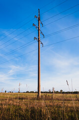 Electric pole in the fileld against the blue sky.