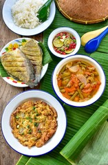 Traditional Thai food set Rice with THAI OMELET and fried  gourami fish with hot and sour curry and thai stylr sauce, top view food table