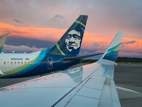 Alaska Airlines Boeing 737 at Ted Stevens Anchorage International Airport in Anchorage, Alaska. Smiling Inuit face on tail of the Alaska Airlines plane at sunset.