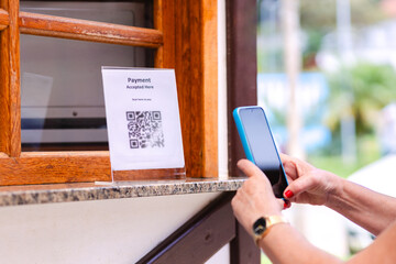 Scanning QR Code on a bar's outdoor counter using a smartphone for instant payments. Illustrates modern technology for online money transfers. Ideal for financial and technology concepts
