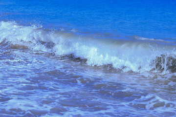 Powerful Ocean blue waves with white foam. Beautiful blue  water background. Bubbling Sea wave. High wave in the sea. Restless water. Turbulent the sea.  Stormy ocean with big restless waves