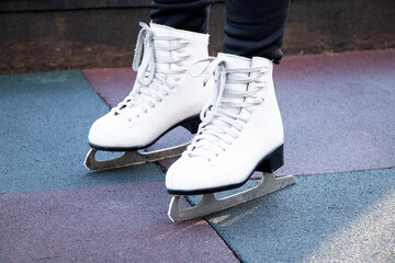 A girl stands in skates on the road outside in winter