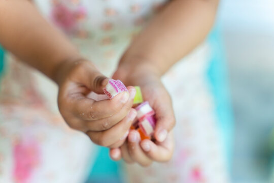 Closeup image of a asian child, girl 3 years holding colorful gelatinous sweets, Jelly gum in hands. happy childhood, balanced diet, sweet life, unhealthy food.