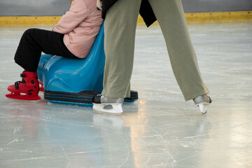 Fototapeta premium Mom rides her child on a skating rink in Ukraine in December in the park