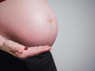 Pregnant woman holding a pill. Pregnancy care concept