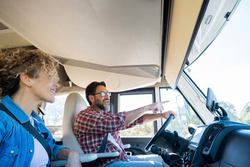 Man driving camper smiles while driving with his wife company. Concept of travel, vacation and life together