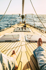 pov point of view of man legs laying and relaxing on the wooden sail boat deck alone with sunset in...