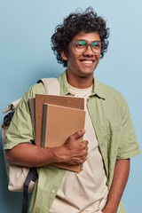 Student lifestyle. Studio vertical waist up of young happy smiling Hindu male standing isolated on...