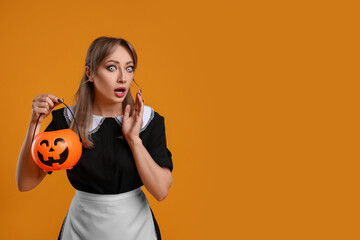 Emotional woman in scary maid costume with pumpkin bucket on orange background, space for text. Halloween celebration