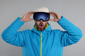 Winter sports. Emotional man in ski suit and goggles on gray background