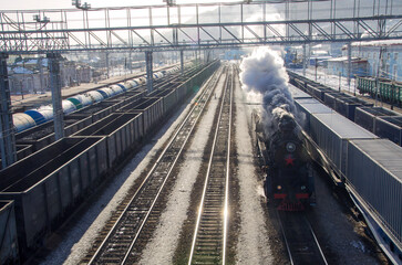 Old Russian steam train rushing , locomotives of other trains standing nearby. Siberia, Russia