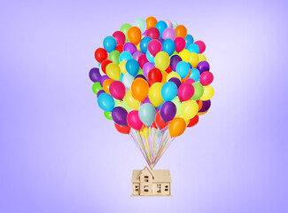 Many balloons tied to model of house flying on violet background