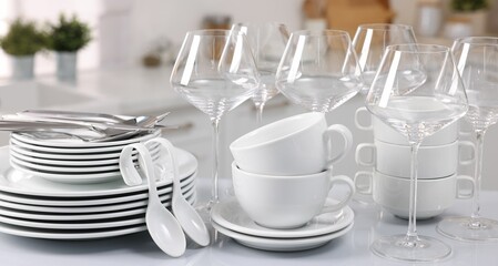 Fototapeta na wymiar Set of clean dishware, glasses and cutlery on table in kitchen