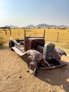 Solitaire, Namibia - August 23, 2022: A vintage car chassis, stripped of its former glory, sits desolately against a backdrop of golden grass and distant mountains