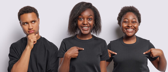 Two positive young African women point at themselves show copy space on t shirt smile gladfully...