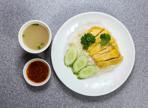 hai nam chicken in thai style with rice, melon soup and chili sauce served in dish isolated on grey background top view of hong kong food