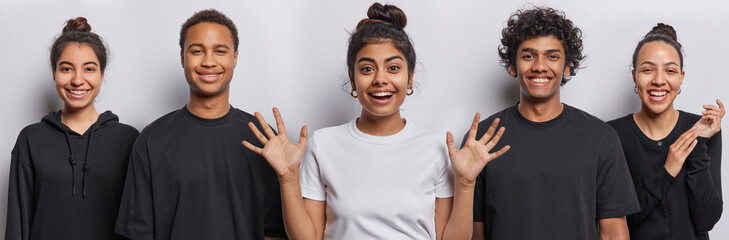 Horizontal shot of positive Iranian woman spreads palms from happiness feels very glad to meet someone glad Hindu and African men all stand in row against white background. People and emotions concept
