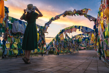 full length rearview of woman in hat at buddhist temple during sunset