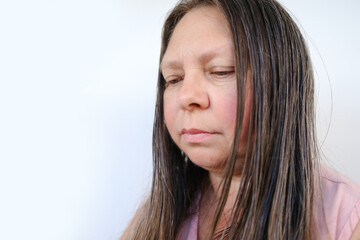 close-up of adult woman looks sadly down, greasy thick long hair, psychological states, sadness and emotions in adult women, hair care and styling, psychotherapy and emotional well-being