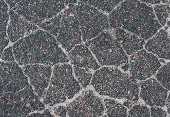 Background, texture, top view of wet asphalt with cracks on a street road. Photography, abstraction, pattern on the ground.