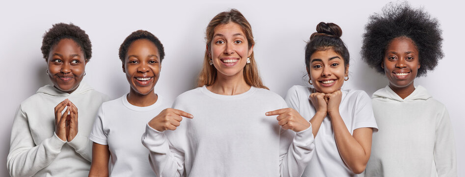 Collage image of cheerful women dressed in casual clothing point at jumper for your logo steeple fingers smile gladfully stand next to each other isolated over white background. Five female models