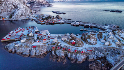 fishing village on an island covered in snow with red traditional rorbu fishings houses, Norway,...