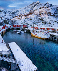 ship in the harbor of a fishing village with mountains in background, Norway, Lofoten