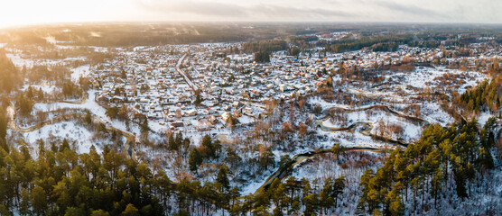 aerial panorama of a residential area blanketed in snow with meandering river at sunset