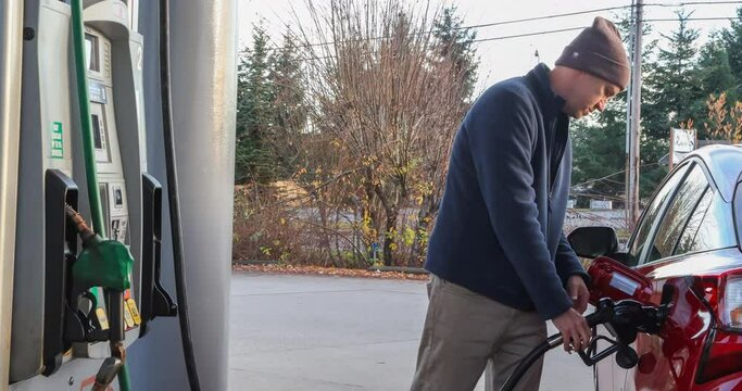 Video clip of a man at the gas station filling his car with fuel, seemingly frustrated at the cost