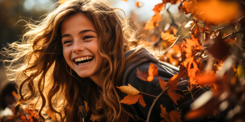 Fototapeta premium Cheerful young girl with a radiant smile, immersed in a sea of autumn leaves, encapsulating the joy and playfulness of fall