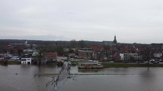 Hattem, the Netherlands - December 27th, 2023: after weeks of heavy rainfall waterlevels have risen to critical hights. This aerial footage shows people at a flooded road near the edge of town. 