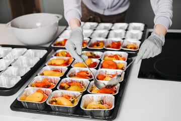 Caterer in a professional kitchen preparing individual servings of roasted vegetables, showcasing...