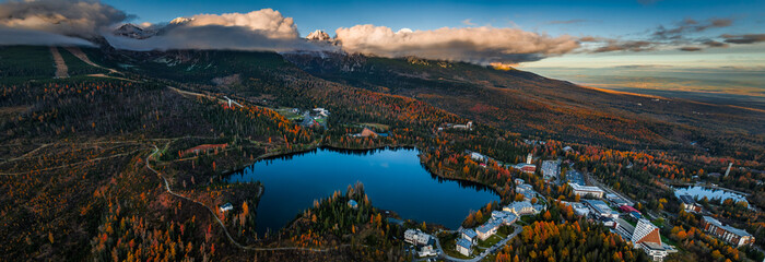 Strbske Lake, Slovakia - Aerial panoramic view of Strbske Lake (Strbske Pleso) on a sunny autumn afternoon with High Tatras and Tatras Tower at background. Autumn colors, blue sky and Tatras mountains