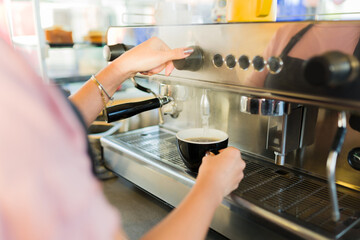Female barista seen from behind making coffee