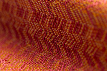 woven fabric of varied twill weaves in bright red and orange colors, detailed close up macro shot...