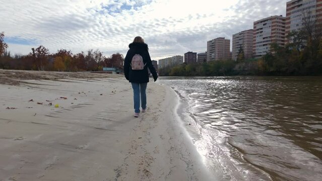Tourist woman strolling quietly along the bank of the Pisuerga River in Valladolid, Spain.