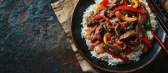  Stir fry Chinese pepper beef steak with onion red and green bell pepper rice in bowl. Creative Banner. Copyspace image © HN Works