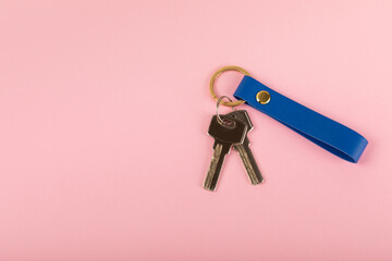 Leather keychain with a key ring on a pink background. Concepts for real estate and moving home or...