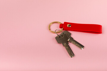 Leather keychain with a key ring on a pink background. Concepts for real estate and moving home or renting property. Buying a property. Mock-up keychain.Copy space.
