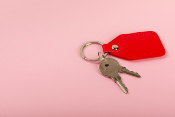 Leather keychain with a key ring on a pink background. Concepts for real estate and moving home or renting property. Buying a property. Mock-up keychain.Copy space.