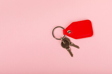 Leather keychain with a key ring on a pink background. Concepts for real estate and moving home or renting property. Buying a property. Mock-up keychain.Copy space.