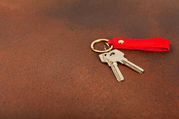 Leather keychain with a key ring on a textured background. Concepts for real estate and moving home...