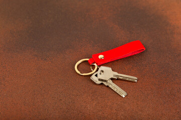 Leather keychain with a key ring on a textured background. Concepts for real estate and moving home...