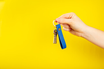 Leather keychain with a key ring on a yellow background. Concepts for real estate and moving home...