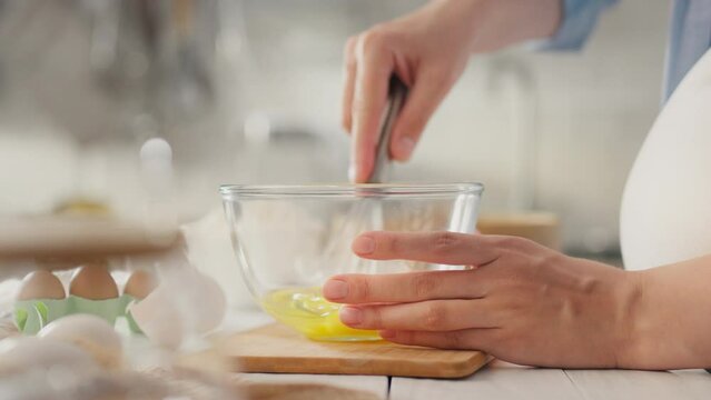 While preparing breakfast for her family, the expectant mother happily beats egg yolks with metal whisk. A housewife expecting baby shows her care by preparing delicious pancakes in her home kitchen.